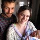 Two parents, presumanbly a father and mother with the mother holding a newborn baby.