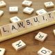 A scrabble rack containing letters that spell out "lawsuit".